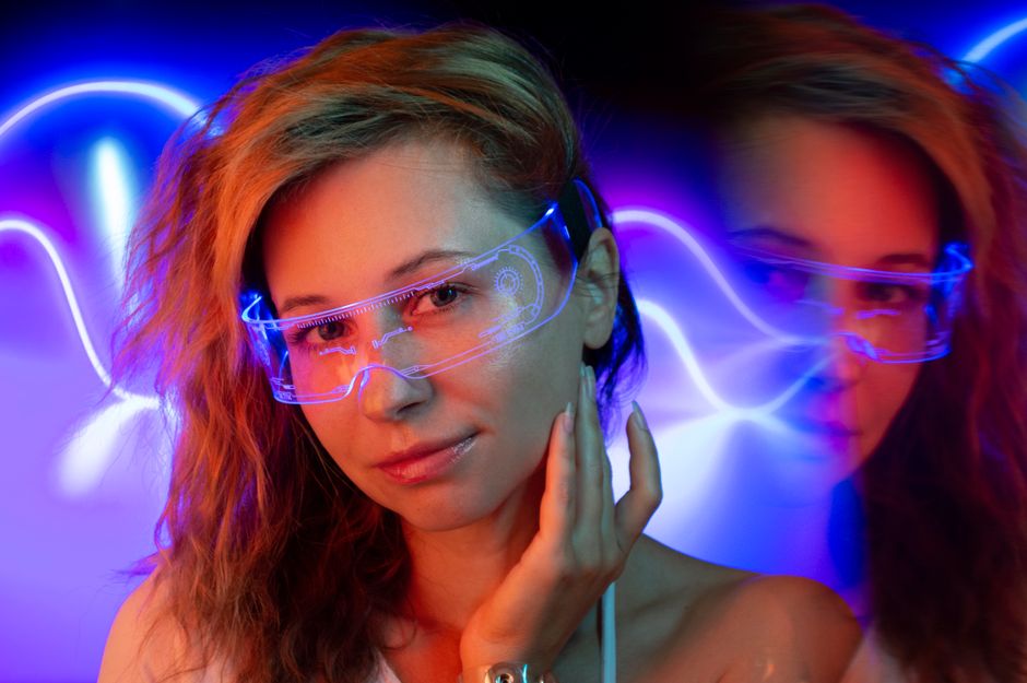 A woman wearing glowing tech glasses in vibrant neon lighting, creating a futuristic vibe.